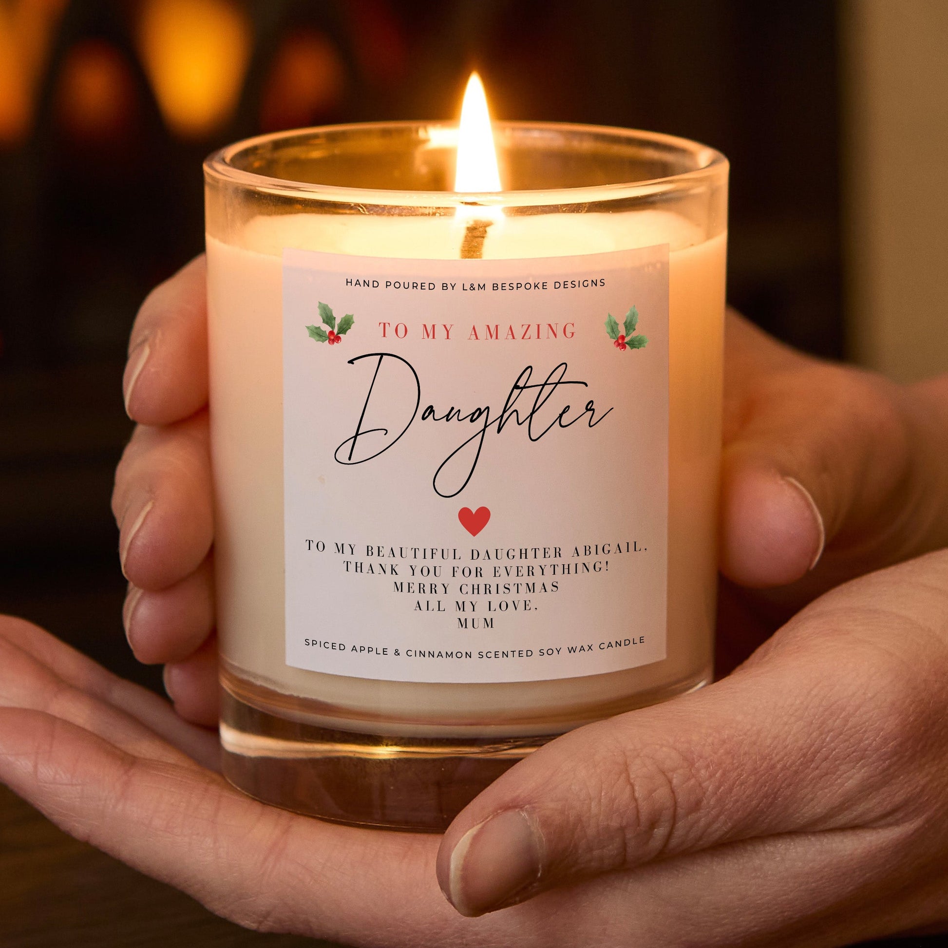 Candle labeled 'To My Amazing Daughter' held in hands with a warm background