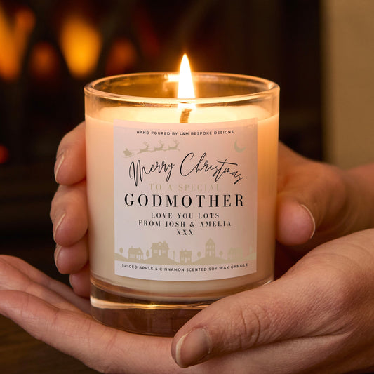 Candle labeled 'Merry Christmas to a Special Godmother' held in hands with a warm background.