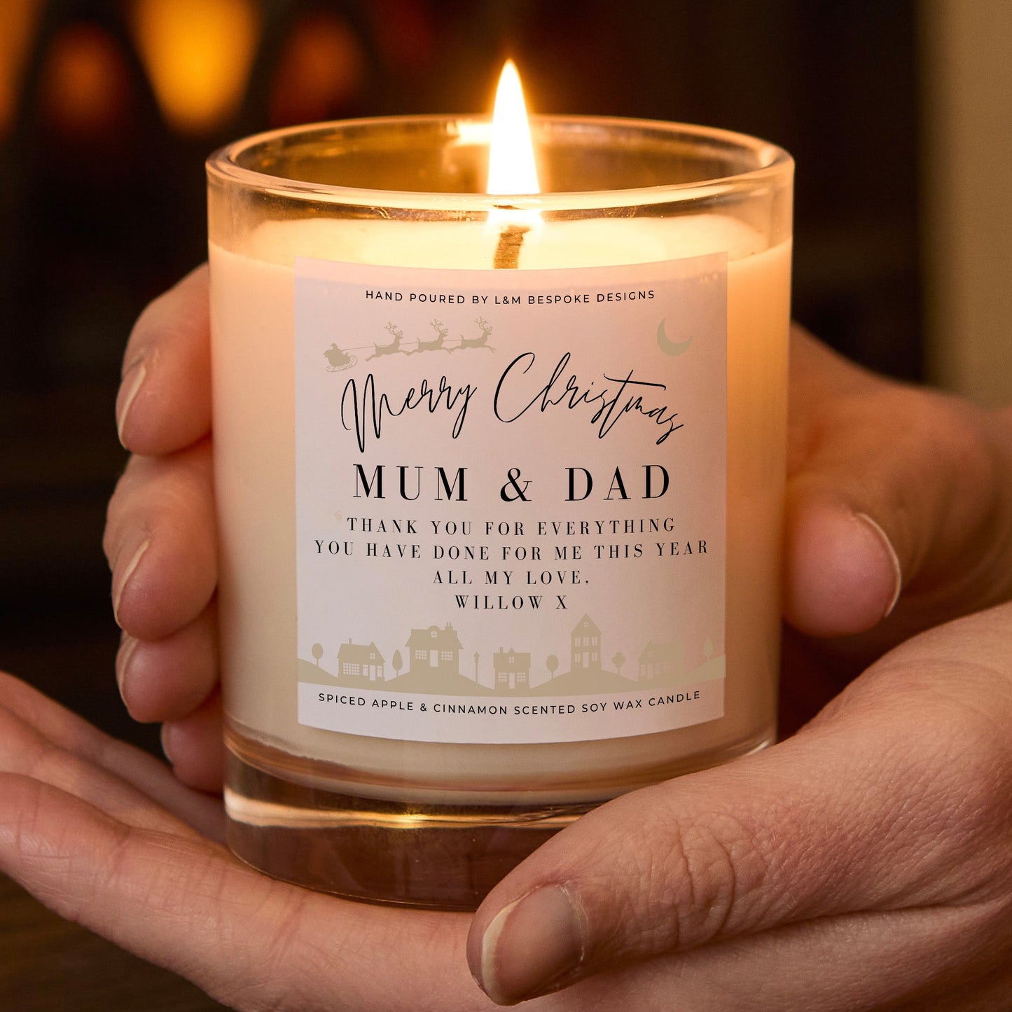 Candle with a personalized label held in hands against a warm background